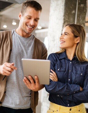 A man and woman focused on a tablet, engrossed in its contents.