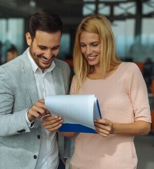 A man and woman intently examine a document, focusing on its contents with great interest and concentration.