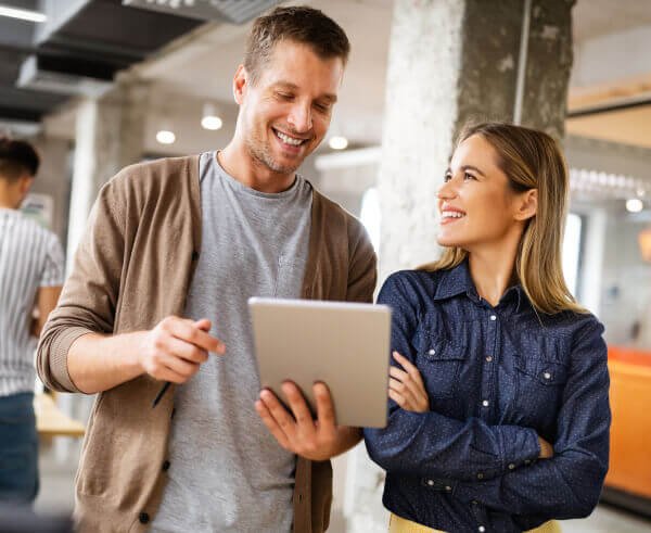 A man and woman focused on a tablet, engrossed in its contents.